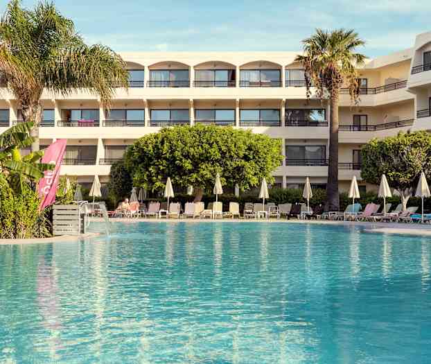 Hotelli, jossa uima-allas ja aurinkotuoleja etualalla. (Tekoälyn luoma teksti)