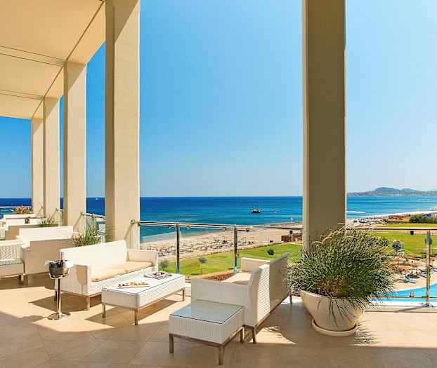 Näkymä terassille, jossa istuimia, rannalle ja merelle. (Tekoälyn luoma teksti)