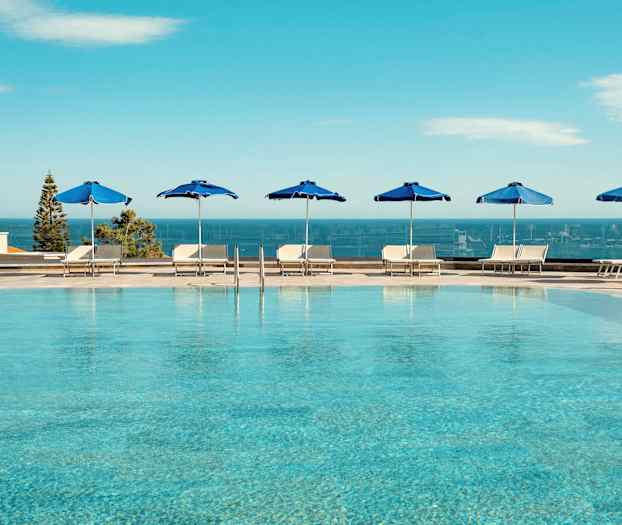 Ulkouima-allas sinisin aurinkovarjoin ja näkymä merelle. (Tekoälyn luoma teksti)