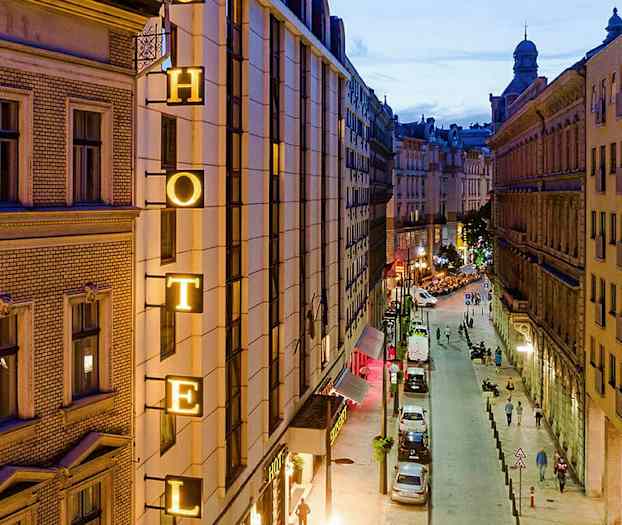 Kuva kaupungin kadusta illalla, jossa hotellin kyltti on rakennuksessa. (Tekoälyn luoma teksti)