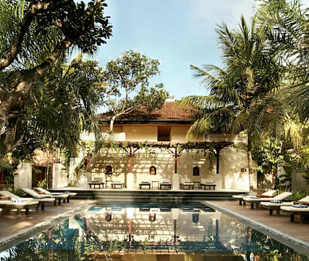 Ulkouima-allas, jonka ympärillä on aurinkotuoleja ja puita sekä taustalla rakennus. (Tekoälyn luoma teksti)