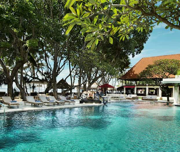 Uima-allas puutarhassa, jota ympäröivät aurinkotuolit ja vehreys. (Tekoälyn luoma teksti)