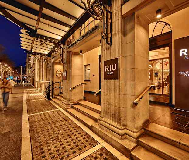 Hotel RIU Plaza Gresham Dublin sisäänkäynti valaistuilla kylteillä, iltamaisema. (Tekoälyn luoma teksti)