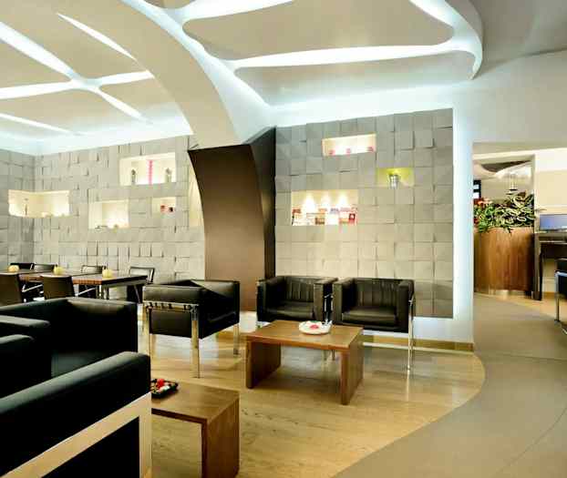 Moderni kahvila, jossa istumapaikkoja, koristeltu kuvioiduilla seinillä ja tyylikkäällä sisustuksella. (Tekoälyn luoma teksti)