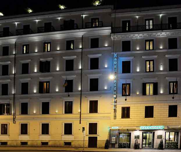 Illalla valaistu kerrostalo, jossa on hotellikyltti ja valaistut ikkunat. (Tekoälyn luoma teksti)