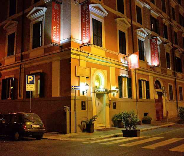 Hotelli nimeltä Hotel Montecarlo sijaitsee kadunkulmassa illalla. (Tekoälyn luoma teksti)