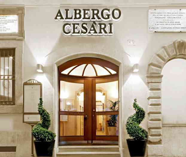 Hotellin sisäänkäynti, jossa huoliteltuja kasveja ja koristeellista arkkitehtuuria. (Tekoälyn luoma teksti)