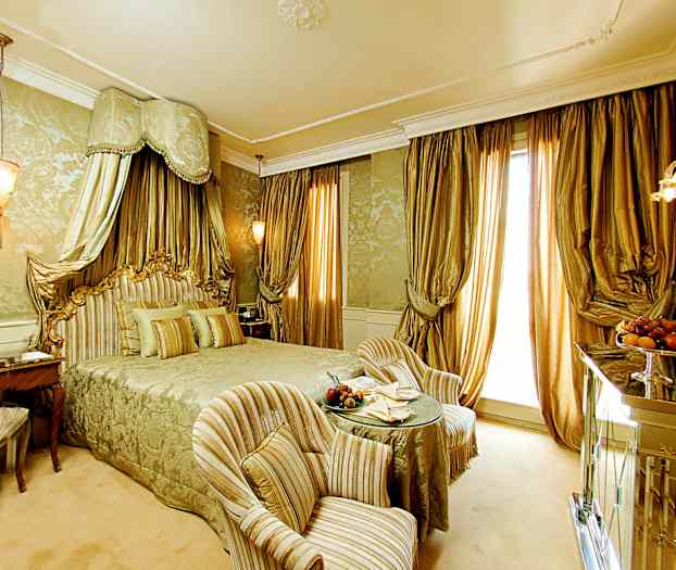 Ylellinen hotellihuone, jossa on suuri sänky ja elegantteja kultaisia yksityiskohtia. (Tekoälyn luoma teksti)