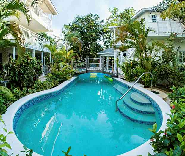 Ulkouima-allas, jota ympäröivät vihreät kasvit ja jossa on rakennuksia taustalla. (Tekoälyn luoma teksti)