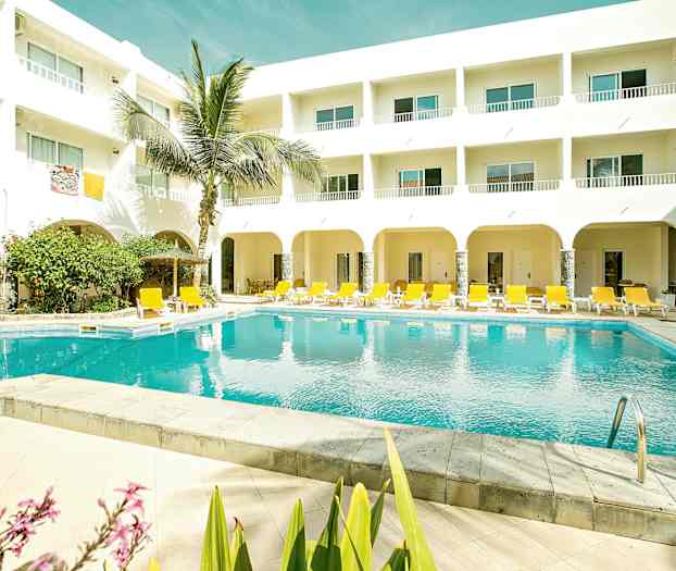 Ulkouima-allas, jossa on keltaisia aurinkotuoleja ja valkoinen parvekkeellinen rakennus. (Tekoälyn luoma teksti)