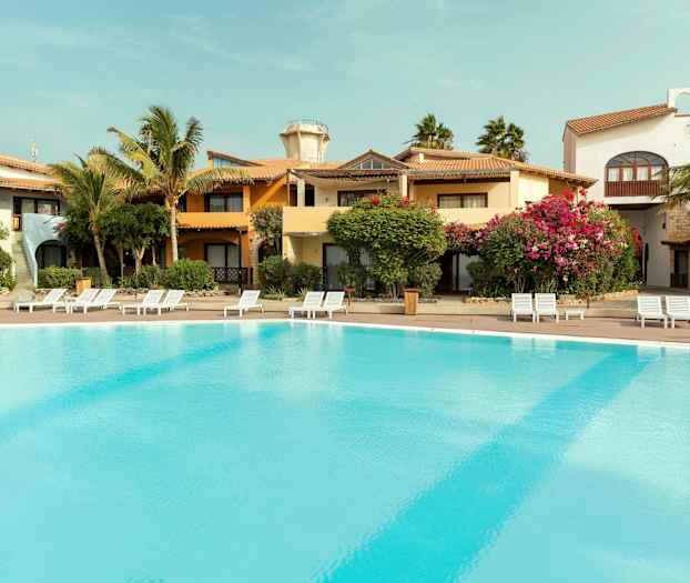 Ulkouima-allas lomakohteessa, ympärillä rakennuksia ja vehreyttä. (Tekoälyn luoma teksti)