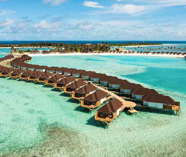 Veden päällä sijaitsevia bungaloita trooppisen rannan taustalla. (Tekoälyn luoma teksti)