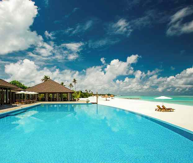 Ylellinen lomakeskus, jossa on uima-allas valkean hiekkarannan vieressä. (Tekoälyn luoma teksti)