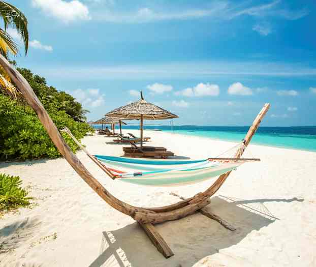 Ranta, jossa riippumatto, aurinkovarjoja ja aurinkotuoleja meren äärellä. (Tekoälyn luoma teksti)