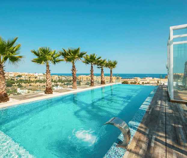 Infinity-allas merinäköalalla ja kaupunkimaisemalla, ympäröitynä palmuilla ja puuterassilla. (Tekoälyn luoma teksti)