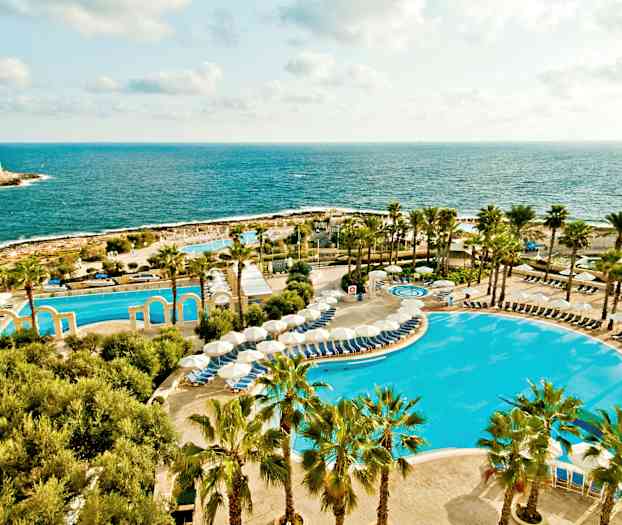 Kuva lomakeskuksesta meren äärellä. Näkymässä altaat, aurinkovarjot ja palmuja. (Tekoälyn luoma teksti)