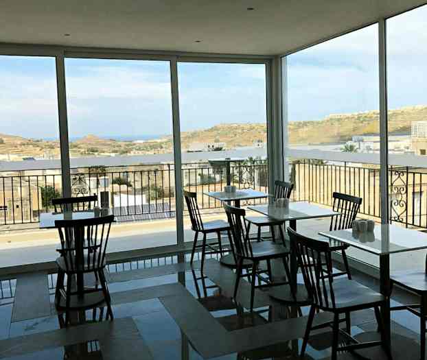 Kahvila, jossa on isot ikkunat ja näkymä maisemaan. (Tekoälyn luoma teksti)