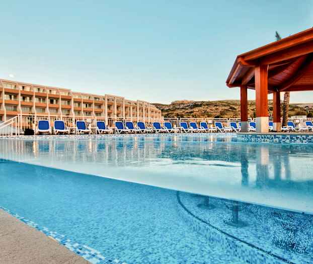 Ulkouima-allas aurinkotuoleilla ja hotellirakennus taustalla. (Tekoälyn luoma teksti)