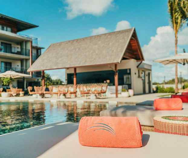 Uima-allasalue, jossa aurinkotuoleja ja rakennus taustalla. (Tekoälyn luoma teksti)