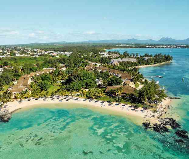 Ilmakuva trooppisesta lomakeskuksesta rannalla, jossa turkoosinvärinen vesi. (Tekoälyn luoma teksti)