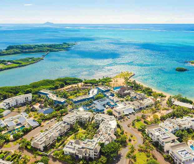 Lentokuva lomakeskusalueesta lähellä rantaa, sininen meri näkyvissä. (Tekoälyn luoma teksti)