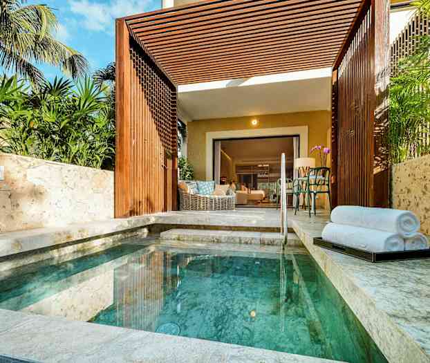 Pieni uima-allas, jota ympäröivät kivipäällysteet ja vehreys, avautuva terassi johtaa huoneeseen. (Tekoälyn luoma teksti)