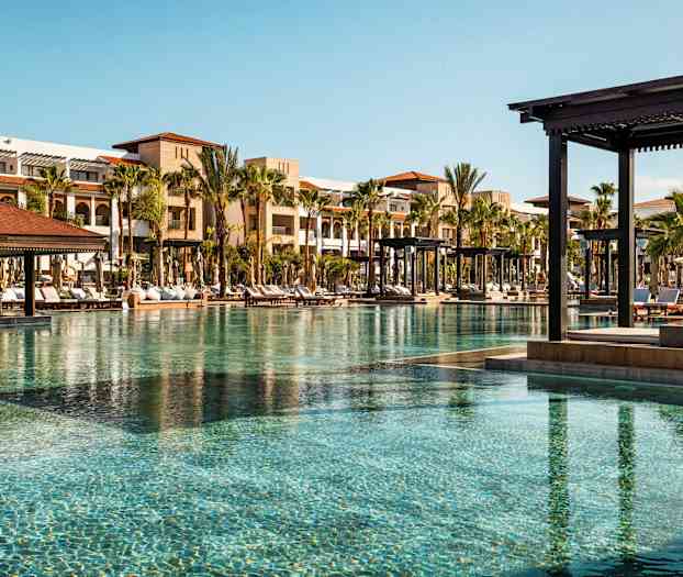 Uima-allasalue, jossa aurinkotuoleja ja rakennuksia taustalla. (Tekoälyn luoma teksti)