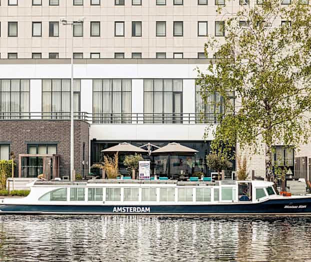 Kuva kanavaveneestä rakennuksen edessä veden äärellä. (Tekoälyn luoma teksti)