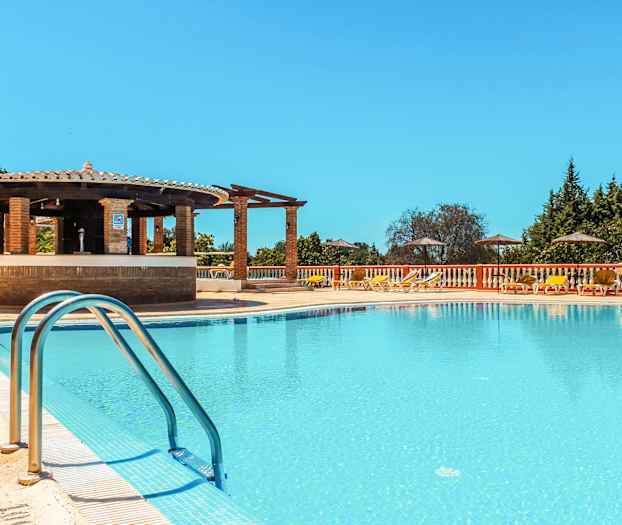 Uima-allasalue, jossa aurinkotuoleja, varjoja ja baari reunalla. (Tekoälyn luoma teksti)