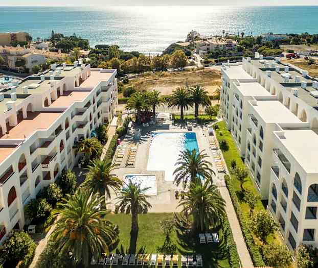 Ilmakuva hotellista, jossa on allasalue ja näkymä merelle. (Tekoälyn luoma teksti)