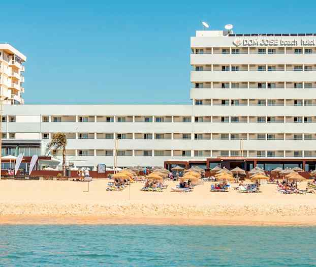 Hotelli rannalla, jossa on aurinkovarjoja ja aurinkotuoleja. (Tekoälyn luoma teksti)