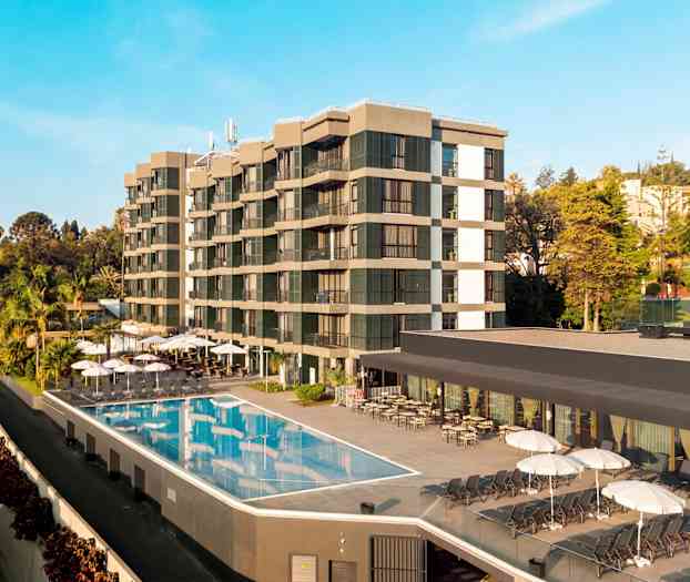 Kuva hotellista, jossa on ulkouima-allas ja aurinkotuoleja, ympäröitynä puilla ja kasvillisuudella. (Tekoälyn luoma teksti)