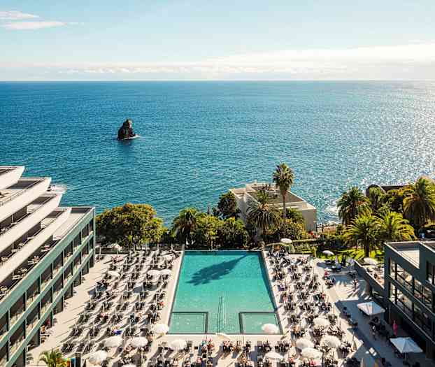 Hotelli meren rannalla, jossa uima-allas ja aurinkotuoleja. (Tekoälyn luoma teksti)