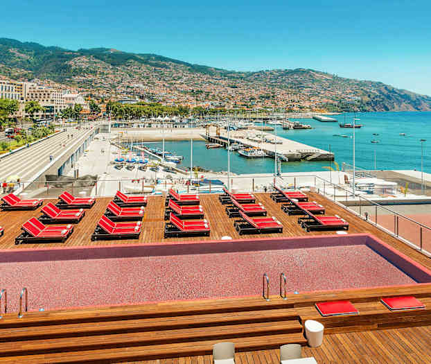 Uima-allasalue aurinkotuoleilla ja näkymä satamaan ja kaupunkiin. (Tekoälyn luoma teksti)