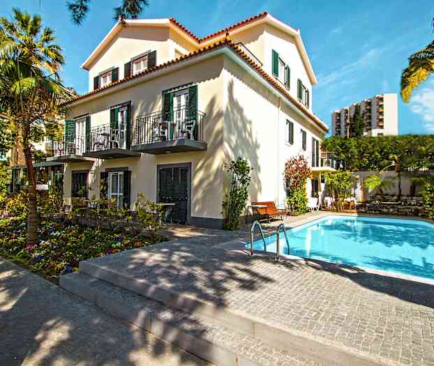 Rakennus puiden ympäröimänä, etualalla uima-allas. (Tekoälyn luoma teksti)