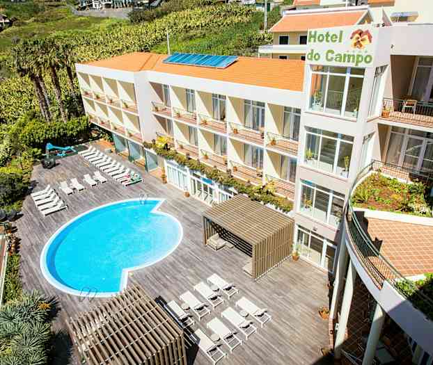 Hotellissa on ulkouima-allas ja aurinkotuoleja terassilla. Rakennuksessa on useita kerroksia ja oranssit katot. (Tekoälyn luoma teksti)