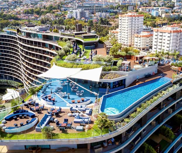 Hotellikompleksi, jossa on terassi, uima-allas ja istuma-alueita. (Tekoälyn luoma teksti)