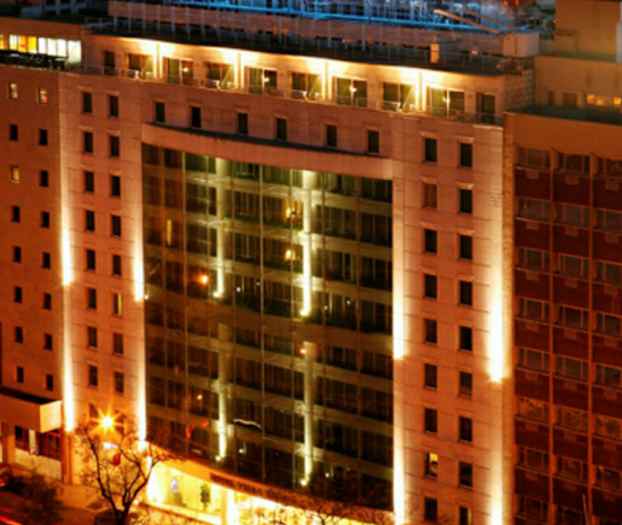 Illalla kuvattu valaistu julkisivullinen rakennus. (Tekoälyn luoma teksti)