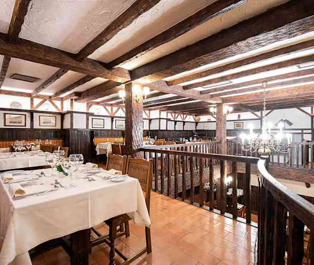 Rustiikkinen ravintola, jossa puiset palkit ja katetut pöydät. (Tekoälyn luoma teksti)