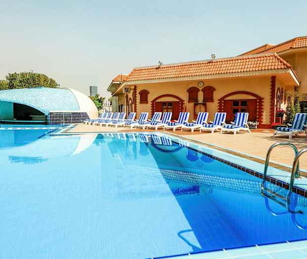 Uima-allas hotellissa, jossa on aurinkotuoleja ja baari taustalla. (Tekoälyn luoma teksti)