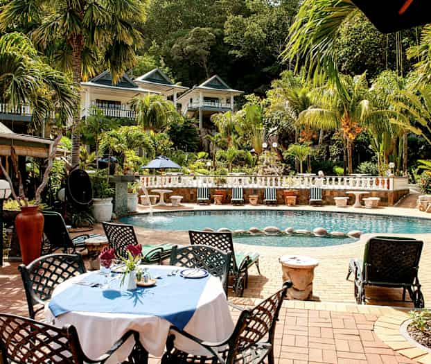 Ulkouima-allas palmujen ja vehreyden ympäröimänä, kalustettu oleskelualue lähellä vettä. (Tekoälyn luoma teksti)