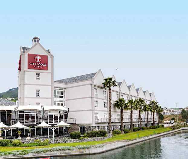 Vaalea julkisivuinen hotelli, jonka edessä kulkee palmuilla reunustettu kanava. (Tekoälyn luoma teksti)