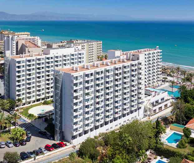 Kuvassa usean kerroksen hotelli rannalla, taustalla näkyy meri. (Tekoälyn luoma teksti)