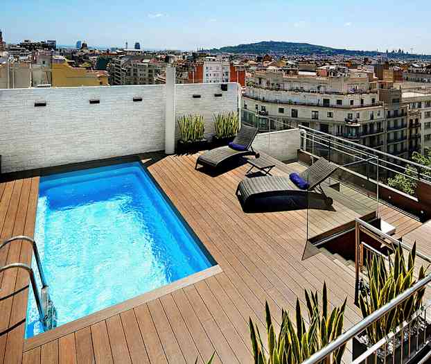 Kattoterassi, jossa on pieni uima-allas, kaksi aurinkotuolia ja näkymä kaupunkiin. (Tekoälyn luoma teksti)