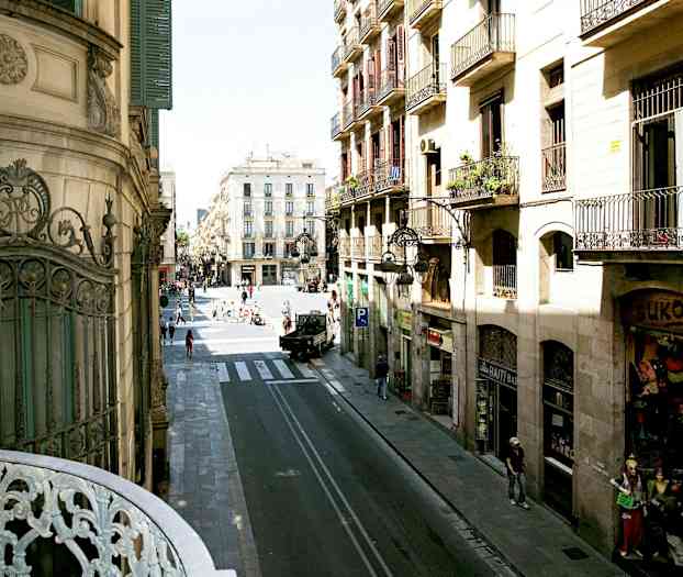 Näköala kadulle, jossa rakennuksia ja ihmisiä kaupunkiympäristössä. (Tekoälyn luoma teksti)