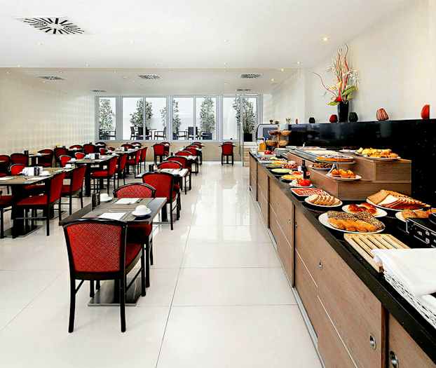 Ravintola, jossa on pitkä buffetti täynnä ruokaa sekä pöytiä ja tuoleja punaisilla istuinpehmusteilla. (Tekoälyn luoma teksti)