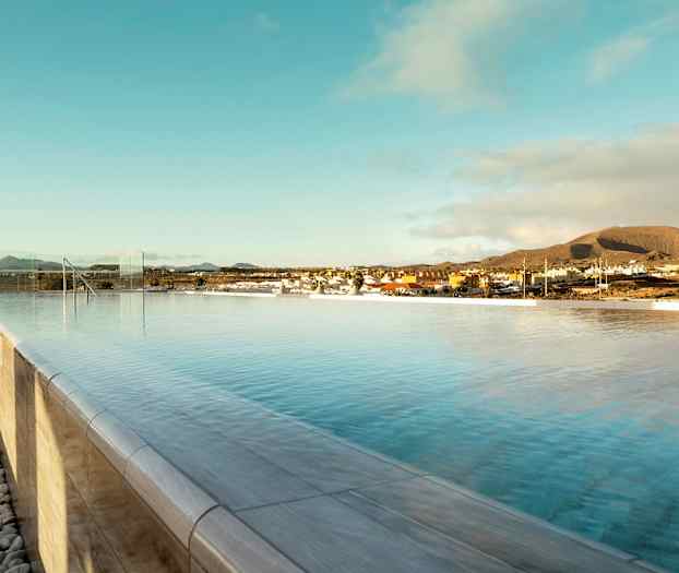 Infinity-allas kirkkaan taivaan alla, taustalla kaupunki ja vuoria. (Tekoälyn luoma teksti)