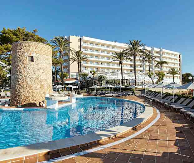 Uima-allas, jota ympäröivät aurinkotuolit, taustalla kivestä rakennettu torni ja hotelli. (Tekoälyn luoma teksti)