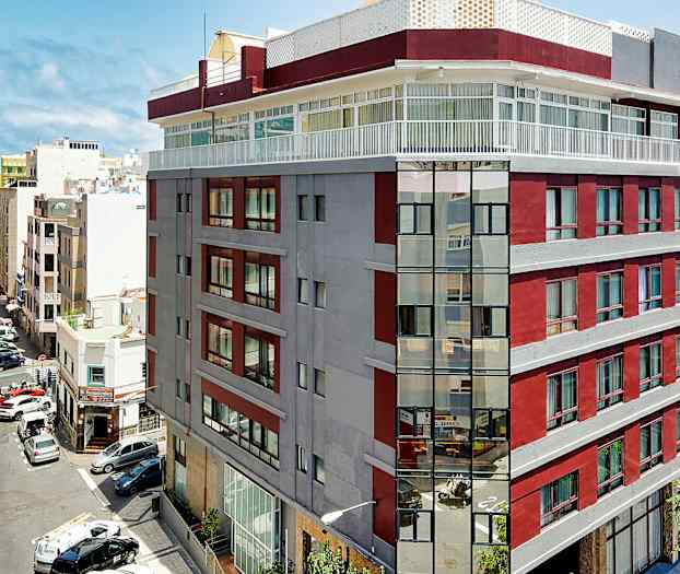 Kuva kaupunkirakennuksesta, jossa on punaisia ja harmaita julkisivuja lähellä merta. (Tekoälyn luoma teksti)