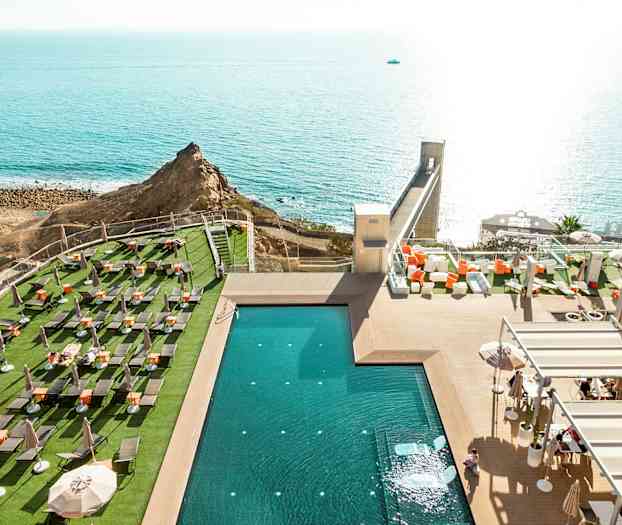 Näkymä uima-altaalle ulkoterassilta, jossa on aurinkotuoleja, ja taustalla näkyy meri. (Tekoälyn luoma teksti)